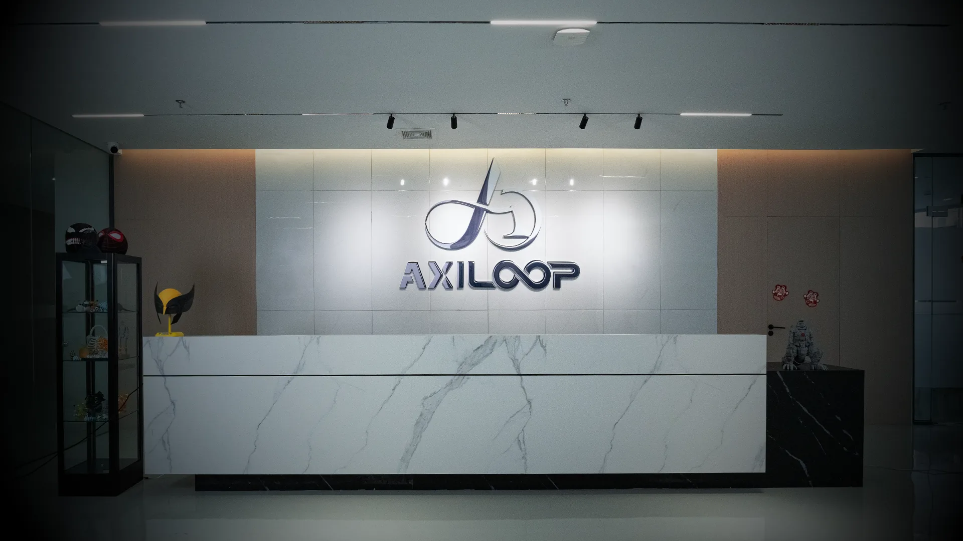 The AXILOOP reception, with the brand's metal logo above a marble front desk.